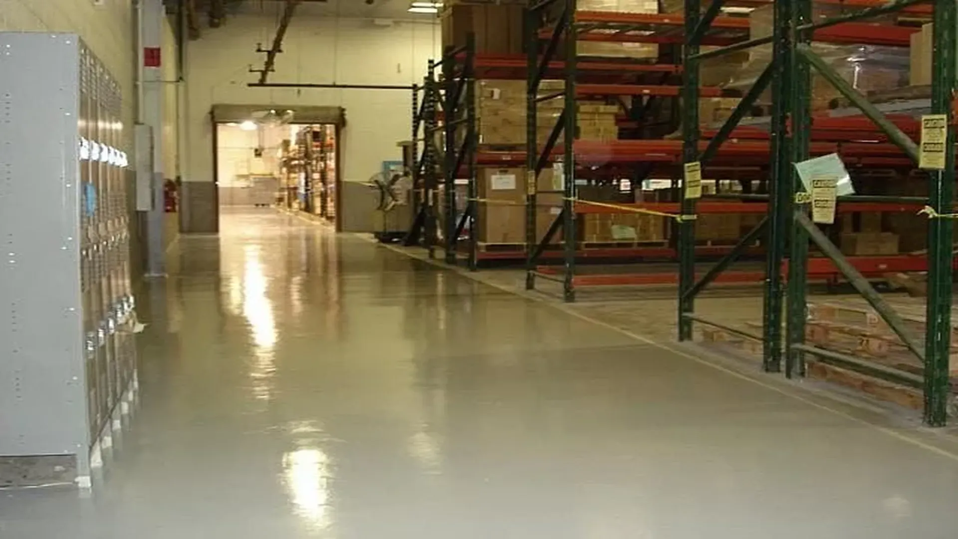 Epoxy-coated warehouse floor with lockers and industrial shelving aisle.